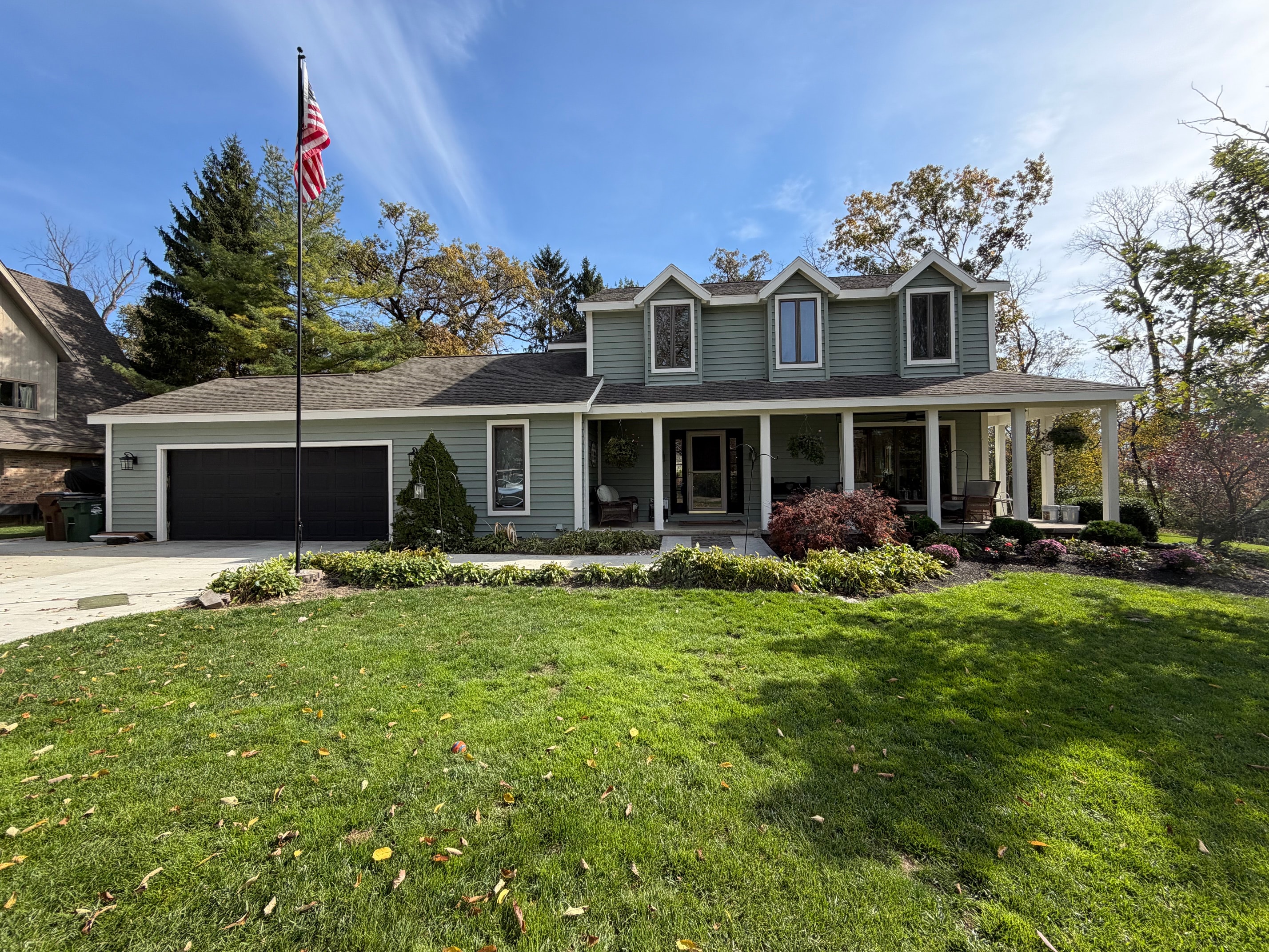 Gray two story house with american flag front lawn