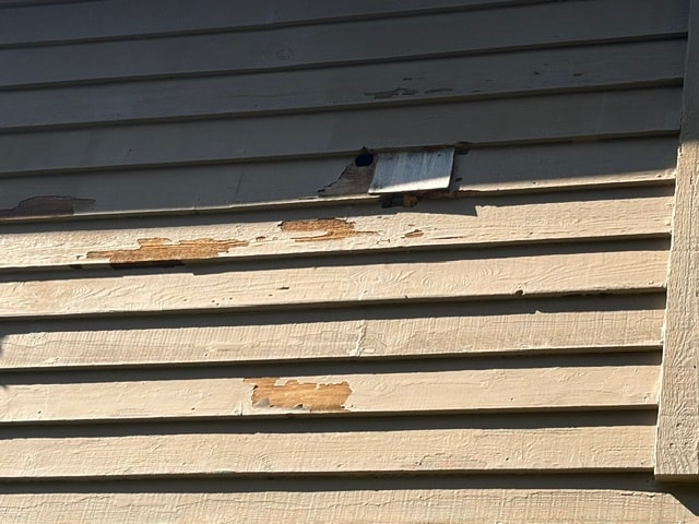 Weathered siding with peeling paint and damaged boards